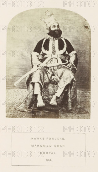 Portrait of Mahomed Khan, an officer at Sekunder Begum, a queen of Bhopal, Madhya Pradesh, India, photograph, page, number: '394.', inscription: 'NAWAB FOUJDAR., MAHOMED KHAN., BHOPAL.', photographer: James John Waterhouse (possibly), Bhopal, 1862, Central India, paper, albumen print, height 115 mm x width 88 mm, ruler, sovereign, human races, peoples, nationalities, A sepia-toned portrait shows a bearded man seated on a patterned chair, wearing an ornate tall headdress with decorative plumes, a dark robe with light trim and an embellished collar, and loose trousers; he holds a curved sword across his lap and rests his hands on its hilt, while a richly patterned textile covers the chair and floor beneath him and a plain backdrop fills the space behind.