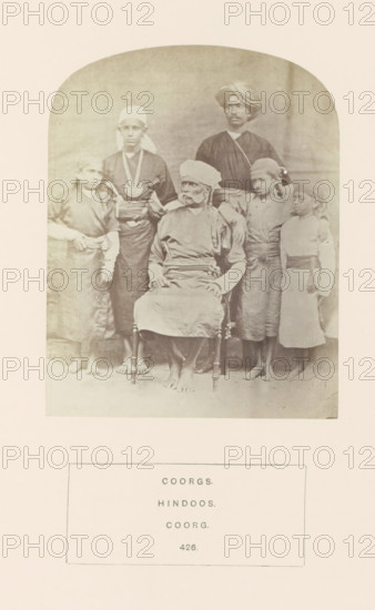 Group portrait of a family from the Kodava community of Kodagu, Karnataka, India, photograph, page, inscription: 'COORGS., HINDOOS., COORG.', number: '426.', photographer: G. Richter (possibly), Kodagu, c. 1865 - in or before 1875, South India, paper, albumen print, height 123 mm x width 97 mm, human races, peoples, nationalities, A faded sepia photograph shows a group portrait of six people framed within a rounded-arch mat; a seated older man wearing a turban and layered garments occupies the center on a wooden chair, his hands resting on his lap and his bare feet visible; flanking him are younger individuals standing, dressed in simple tunics and sashes with head coverings or wraps, some with long hair or headcloths, and one taller figure standing behind wearing a darker loose garment and a turban; the backdrop is plain and the floor shows faint shadows beneath their feet.