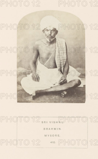 Portrait of an unknown priest from the Vaishnav Brahmin community of Mysore, Karnataka, India, photograph, page, number: '410.', inscription: 'SRI VISHNU., BRAHMIN., MYSORE.', Mysore, c. 1865 - in or before 1875, photographer, South India, paper, albumen print, height 102 mm x width 76 mm, Brahma (supreme being, creator, etc., Hinduism, Buddhism, Jainism), human races, peoples, nationalities, A sepia-toned photograph of an older man seated cross-legged on a plain surface, wearing a light-colored wrapped cloth around his lower body and a turban on his head, with a patterned cloth draped over one shoulder; he is bare-chested and has a thin beard and mustache, with his hands resting on his knees and one hand slightly raised, looking forward, and the image is framed by a rounded-arch border on a light background.