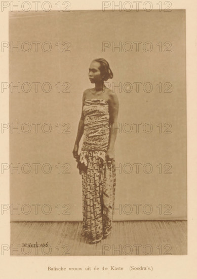 Portrait of an unknown woman, Balinese woman from the 4th Caste, page, photomechanical print, maker: Christiaan Johan Neeb, c. 1892 - in or before 1897, paper, collotype, photoprint, height 121 mm x width 167 mm, historical persons, adult woman, Indonesia, A sepia-toned photograph of a woman standing in front of a plain backdrop, shown full length and facing slightly to the side, wearing a strapless wrapped bodice and a patterned wrap skirt that reaches the floor, with her hair pulled back and her arms relaxed at her sides.