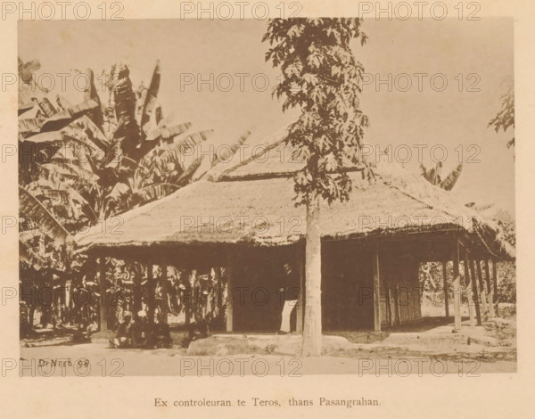 Ex inspector in Teros, now Pasangrahan, View of four unknown persons sitting in front of a house, page, photomechanical print, maker: Christiaan Johan Neeb, c. 1892 - in or before 1897, paper, collotype, photoprint, height 122 mm x width 163 mm, historical persons, other dwelling types, Indonesia, A sepia-toned photograph showing a thatched-roof structure with a sloping straw roof supported by slender wooden posts, a tall slender tree with clustered leaves standing in front of the structure, dense large-leaved plants and banana-like foliage surrounding and rising behind the building, shaded open area beneath the roof where a piece of fabric or cloth hangs and a shadowed entrance is visible, a raised earthen or stone base at the tree trunk, and a plain sky occupying the upper background.