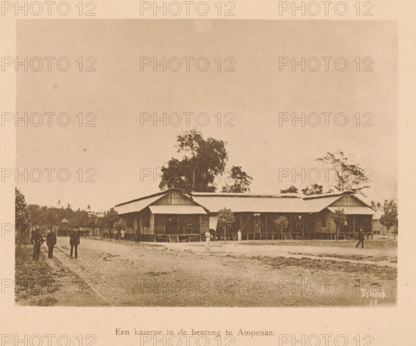 View of a barracks in Ampenan, A barracks in the benteng in Ampenan, page, photomechanical print, maker: Christiaan Johan Neeb, c. 1892 - in or before 1897, paper, collotype, photoprint, height 120 mm x width 158 mm, other dwelling types, Lombok, Ampenan, A sepia photograph showing a large wooden building with a corrugated roof elevated on stilts, a covered veranda, and steps leading up to entrances, set behind a dirt foreground; several trees rise behind and beside the building, and small shrubs or potted plants line the veranda; scattered people stand or walk in front of and near the building, and a faint pair of tracks run across the left side of the ground.