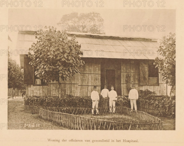 Four unknown European men in front of a house, Housing of the Medical Officers in the Hospital, page, photomechanical print, maker: Christiaan Johan Neeb, c. 1892 - in or before 1897, paper, collotype, photogravure, height 120 mm x width 167 mm, officer, housing, A sepia-toned photograph of a single-story wooden building with a corrugated metal roof, flanked by leafy trees and shrubs, showing a central doorway and shuttered windows; in front of the building four men in light-colored uniforms and caps stand behind a low decorative fence surrounding a neatly trimmed hedge and garden path.