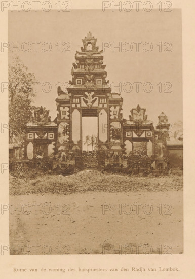 Ruin of the house of the house priest of the Raja of Lombok, View of ruins of the house of a house priest of the Raja of Lombok, page, photomechanical print, maker: Christiaan Johan Neeb, c. 1892 - in or before 1897, paper, collotype, photoprint, height 164 mm x width 116 mm, ruin of a building, architecture, Indonesia, An aged photograph shows a carved stone gateway with a central tall opening flanked by smaller openings, topped by layered ornamental tiers with sculpted motifs and decorative reliefs, standing on a grassy mound with scattered stones; low ornamental walls and sculpted pedestals extend to either side, and trees are visible behind and beside the structure, while the foreground shows a bare expanse of ground leading up to the mound.