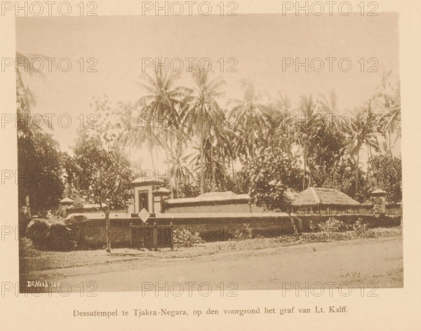 Dessa temple in Tjakra-Negara, in the foreground the grave of Lt. Kalff, View of the Dessa Temple and the grave of Lieutenant Kalff, page, photomechanical print, maker: Christiaan Johan Neeb, c. 1892 - in or before 1897, paper, collotype, photoprint, height 119 mm x width 161 mm, trees, grave, tomb, temple, shrine, non-Christian religions, Indonesia, A sepia-toned photograph showing a low wall and gate in front of a compound with a small tower-like entrance and a thatched-roof structure behind it, dense vegetation and tall palm trees rising behind the buildings, a dirt foreground with scattered vegetation, and a pale border surrounding the image.