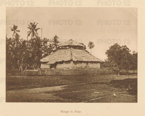 View of a mesigit, Mesigit te Praja, page, photomechanical print, maker: Christiaan Johan Neeb, c. 1892 - in or before 1897, paper, collotype, photoprint, height 119 mm x width 165 mm, other dwelling types, Indonesia, A sepia-toned photograph showing a thatched-roof building with a wide, sloping main roof and a smaller upper conical thatch, walls with a textured surface, and an open doorway; the structure is surrounded by a woven fence and sits amid grassy ground with a dirt path in the foreground; tall palm trees and other dense vegetation rise behind and to the sides of the building, and open sky fills the upper portion of the image.
