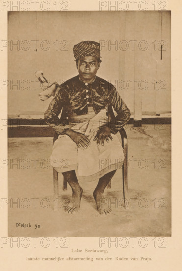 Laloe Soetawang, last male descendant of the Raden van Praja, Portrait of Laloe Soetawang, page, photomechanical print, maker: Christiaan Johan Neeb, c. 1892 - in or before 1897, paper, collotype, photoprint, height 170 mm x width 123 mm, Person, historical persons, adult man, Indonesia, A sepia-toned photograph of a barefoot man seated on a wooden chair facing forward, wearing a patterned headwrap and a dark, long-sleeved top with a row of buttons down the front, a light cloth wrapped around his waist, hands resting on his lap with fingers spread, bare feet visible on the floor, a plain backdrop behind him with a hanging cord and a small object suspended to one side, and a small signature visible in the lower corner of the image.