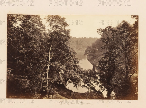 The Clyde at Bothwell, View of the Clyde, photograph, page, South Lanarkshire, c. 1862 - in or before 1867, photographer, paper, albumen print, height 112 mm x width 178 mm, river, landscapes with waters, waterscapes, seascapes (in the temperate zone), A sepia-toned photograph showing a tree-filled scene with a river running through a wooded valley; tall trees with leafy canopies frame both sides, some trunks visible in front, and dense foliage fills much of the image with darker textured leaves contrasted against a lighter sky above; the river surface appears reflective and snakes between the tree-covered banks toward the distant treeline, and a small structure is partially visible near the far bank amid the trees.