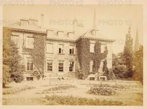 View of Bishop's Palace at Lichfield, photograph, page, photographer: John Benjamin Stone, Lichfield, c. 1865 - in or before 1870, John Benjamin Stone, photographer, Staffordshire, paper, albumen print, height 126 mm x width 173 mm, facade (of house or building), A wide pale photograph of a large stone building with a pitched roof and several chimneys, its facade partly covered in climbing ivy, with multiple tall windows on two levels and dormer windows in the roof; a trimmed lawn and garden beds lie in the foreground, and there are tall trees near the building and two narrow pointed church spires rising behind the trees to the right.
