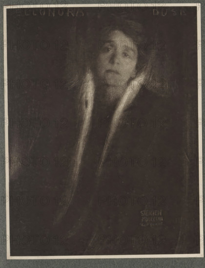 Eleonore Duse, Portrait of Eleonore Duse, page, photomechanical print, inscription: 'Photographische Mitteilungen XL', photographer: Edward Steichen, New York (city) (possibly), cliché maker: anonymous, c. 1898 - in or before 1903, North America, paper, photoaquatint, height 181 mm x width 140 mm, Person, Eleonora Duse, historical persons - BB - woman, A dark, grainy portrait of a person with a pale face and an expressionless gaze, framed by soft, light strokes suggesting hair and a collar or scarf that extends downwards, set against a deep, nearly black background with faint vertical and diagonal smudges.
