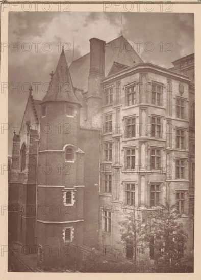 Lille, l'hotel-de-ville, Palais Rihour in Lille, page, photomechanical print, inscription: 'Journal le Nord Contemporain, No 13, année 1882', inscription: 'Le Nord Contemporain, Revue Artistique & Archéologique', inscription: 'La partie du onument appelée 'Le Conclave'', c. 1878 - in or before 1882, paper, Woodburytype, height 124 mm x width 152 mm, Print on fifth unnumbered page after page 208., palace, A sepia-toned photograph showing two adjoining historic buildings with varied architectural features. On the left a cylindrical brick turret with narrow arched windows and stone trim rises to a conical roof topped by a finial, adjoining a steeply pitched roof and a tall chimney stack. On the right a stone façade with multiple recessed window bays, decorative moldings, and corner pilasters presents stacked rectangular windows and ornate stonework around an entrance partially obscured by trees. A wrought-iron fence runs along the foreground, and cloudy sky fills the upper background.