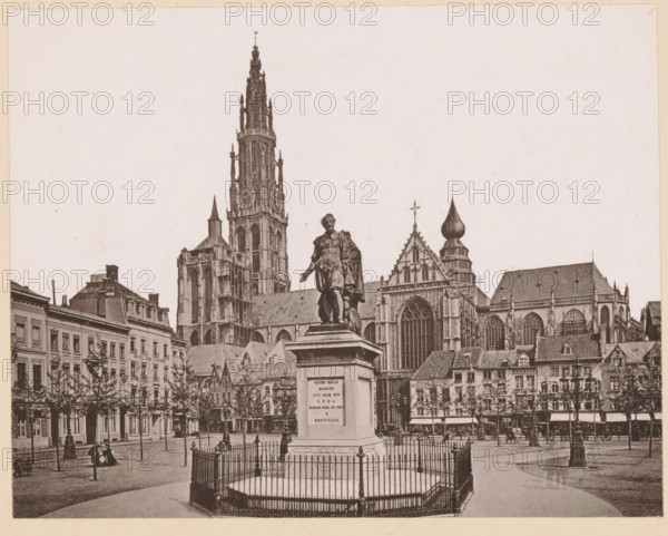 Anvers, La Statue de P.-P. Rubens, Statue of Peter Paul Rubens on the Groenplaats in Antwerp, page, photomechanical print, inscription: '(Oeuvre de G Geefs)', inscription: 'Le Nord Contemporain, Revue Artistique', photographer: NC, Antwerp, c. 1878 - in or before 1883-04-05, paper, collotype, photoprint, height 172 mm x width 220 mm, Print on third unnumbered page after page 96., Person, Peter Paul Rubens, monument, statue, Groenplaats, A sepia-toned city square scene showing a large ornate cathedral with tall spires and detailed gothic windows rising behind a row of multi-story buildings, a prominent statue of a robed figure standing on a pedestal at the center foreground surrounded by an iron fence, tree-lined sidewalks, street lamps, and clusters of horse-drawn carriages and people scattered along the pavement.