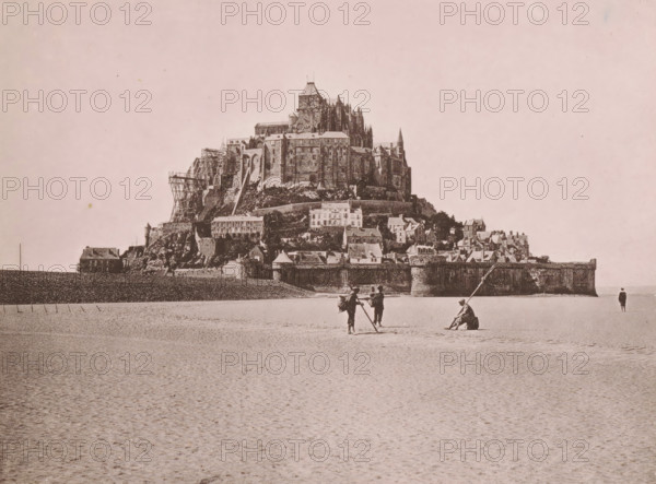 View of Mont Saint-Michel, Le Mont Saint-Michel, Au Péril de la Mer, page, photomechanical print, inscription: 'Le Nord Contemporain, Revue Archéologique & Pittoresque', inscription: 'Journal le Nord Contemporain, No 31, année 1883.', photographer: NC, Mont-Saint-Michel (abbey), c. 1878 - in or before 1883-04-20, paper, collotype, photoprint, height 165 mm x width 219 mm, Print on fifth unnumbered page after page 112., island, prospect of village, silhouette of village, A large rocky island topped by a complex stone building with towers, spires, and scaffolding rises from a flat sandy foreground, with terraces of smaller buildings and defensive walls along its base; in the foreground on the sand three people stand and one sits near long poles while another person stands alone near the waterline, and a solitary house sits at the far left against a low seawall.