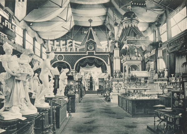 View of the Italian, Russian and Austrian parts of the main exhibition of the Antwerp World's Fair in 1894, Coup d'oeil sur les Sections, Italienne Russe Autrichienne, Exposition Universelle d'Anvers 1894, page, photomechanical print, photographer: Charles Bernhoeft, Antwerp, cliché maker: Charles Bernhoeft, Luxembourg (Belgian province), 1894, Charles Bernhoeft, photographer, cliché maker, paper, collotype, photoprint, height 153 mm x width 216 mm, Print on third unnumbered page after page 34., piece of sculpture, reproduction of a piece of sculpture, world fair, world exhibition, World Exhibition 1894 (Antwerp), Period, 1894-05-05 - 1894-11-05, A large indoor exhibition hall filled with sculpted figures and ornate architectural displays under a vaulted fabric ceiling, showing rows of marble statues on pedestals in the foreground and decorative columns, draped canopies, and a domed pavilion toward the center and right; tall windows line the side walls, decorative friezes and patterned...