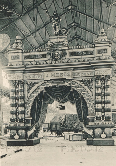 View of a setup of alcohol manufacturer J. Meeûs at the Antwerp World Exhibition in 1894, Installation J. Meeus, Anvers, Exposition Universelle d'Anvers 1894, page, photomechanical print, photographer: Charles Bernhoeft, Antwerp, cliché maker: Charles Bernhoeft, Luxembourg (Belgian province), 1894, Charles Bernhoeft, photographer, cliché maker, paper, collotype, photoprint, height 222 mm x width 153 mm, Print on third unnumbered page after page 122., alcoholic drinks, world fair, world exhibition, World Exhibition 1894 (Antwerp), Period, 1894-05-05 - 1894-11-05, A large ornate entranceway occupies the center of the image, topped with a sculpted figure standing on a pediment and flanked by decorative urns and balustrades, with a vaulted roof structure visible above. The facade features heavy columns wrapped with banded patterns and rounded elements, carved foliage motifs, and a central crest with an anchor motif surrounded by decorative garlands. A draped curtain hangs under the arch, e...