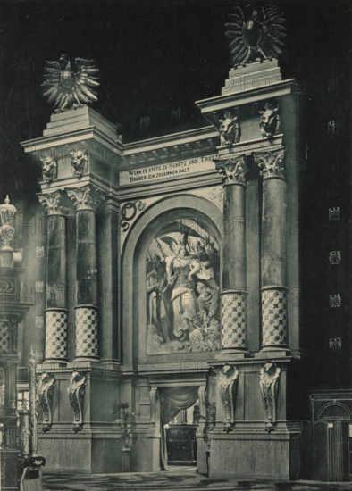 View of the entrance to a music hall in the German part of the Antwerp World Exhibition in 1894, Entrée du Salon de Musique, Section Allemande, Exposition Universelle d'Anvers 1894, page, photomechanical print, photographer: Charles Bernhoeft, Antwerp, cliché maker: Charles Bernhoeft, Luxembourg (Belgian province), 1894, Charles Bernhoeft, photographer, cliché maker, paper, collotype, photoprint, height 215 mm x width 152 mm, gate, entrance, world fair, world exhibition, music-hall, World Exhibition 1894 (Antwerp), Period, 1894-05-05 - 1894-11-05, A grand architectural façade with tall ornate columns and decorative capitals, flanked by sculpted animal heads and topped by large stylized eagles, features a large arched niche containing a painted scene of robed figures and a winged figure; patterned columns with spiral designs rise from a heavy base adorned with carved corbels and draped fabric over a recessed doorway, while ornamental urns, lampposts, and additional sculptural details ar...
