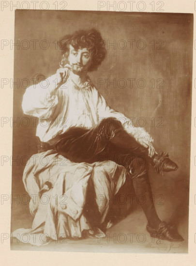 Photo reproduction of a painting of a smoking man by Willem Linnig (II), photograph, reproduction, page, photographer: Alexandre van Antro, after painting by Willem Linnig (II), c. 1891 - in or before 1896, paper, daylight collodion silver print, height 160 mm x width 118 mm, adult man, cigarette, A sepia-toned image of a seated man wearing a loose white blouse and dark fitted breeches, with one leg crossed over the other and pointed shoes with decorative bows; he has curly hair, a mustache and goatee, and holds a small object near his face with one hand while the other rests on his knee; a draped cloth covers part of the chair and cascades over his lap, and a plain background fills the space behind him.