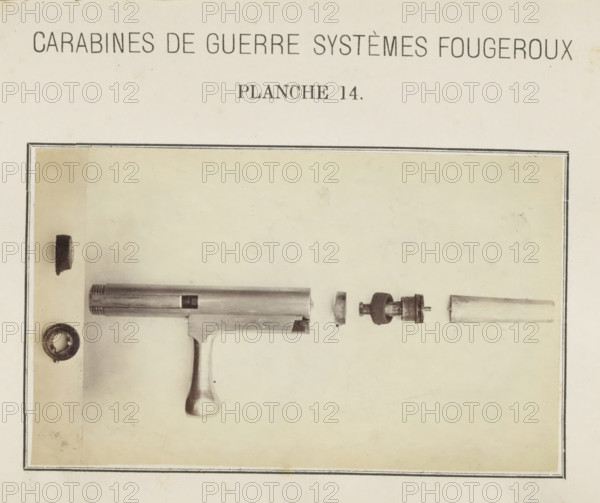 Safety catch of a rifle in parts, photograph, page, number: 'Planche 14.', inscription: 'Carabines de guerres systèmes Fougeroux', photographer: Edouard Magis, Liège, c. 1857 - in or before 1867, paper, albumen print, height 158 mm x width 96 mm, Image in section at the back., firearms: rifle, A faded sepia-toned page with a rectangular bordered area containing a partially visible metal firearm frame and a rounded grip, accompanied by several cylindrical and ring-shaped metal components arranged horizontally above and beside the frame, all set against a light, slightly mottled background.