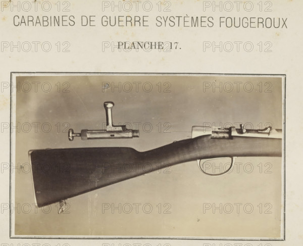 Butt of a rifle and the safety catch, photograph, page, inscription: 'Carabines de guerres systèmes Fougeroux', number: 'Planche 17.', photographer: Edouard Magis, Liège, c. 1857 - in or before 1867, paper, albumen print, height 96 mm x width 158 mm, Image in section at the back., firearms: rifle, A sepia-toned photograph framed on aged paper showing a close-up of a rifle stock and part of its metal action and trigger guard against a plain background, with a separate metal bolt component positioned above the stock, visible metal finish and wooden grain on the stock, and a rectangular border around the photograph.