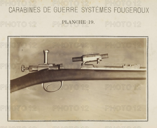 Barrel of a gun, photograph, page, inscription: 'Carabines de guerres systèmes Fougeroux', number: 'Planche 19.', photographer: Edouard Magis, Liège, c. 1857 - in or before 1867, paper, albumen print, height 96 mm x width 158 mm, Image in section at the back., firearms: rifle, A sepia-toned photograph framed by a thin dark border shows a close-up of a rifle horizontal across the image, featuring a wooden stock with a smooth curved trigger guard and visible metal trigger, a bolt mechanism with a rounded handle, a cylindrical sight mounted atop the barrel, and a metallic barrel section extending toward the right; the background is a mottled neutral tone and the surrounding paper shows slight discoloration and spots.