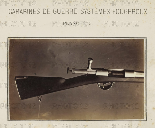 Butt of a rifle, photograph, page, number: 'Planche 5.', inscription: 'Carabines de guerres systèmes Fougeroux', photographer: Edouard Magis, Liège, c. 1857 - in or before 1867, paper, albumen print, height 158 mm x width 96 mm, Image in section at the back., firearms: rifle, A sepia-toned photograph shows the rear half of a rifle mounted horizontally inside a bordered frame on a light background; the wooden stock is dark with a smooth curved shoulder, a metal sling swivel attached near its end, a metal bolt handle and cylindrical bolt assembly with knurled adjustment knob, a trigger and curved trigger guard, and a contrasting lighter metal band near the muzzle area, all set against a plain darker backdrop within the photograph.