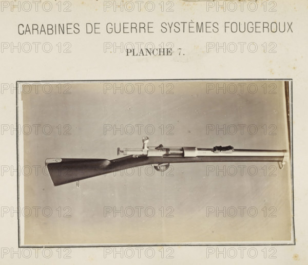 Part of a rifle, photograph, page, inscription: 'Carabines de guerres systèmes Fougeroux', number: 'Planche 7.', photographer: Edouard Magis, Liège, c. 1857 - in or before 1867, paper, albumen print, height 158 mm x width 96 mm, Image in section at the back., firearms: rifle, A black-and-white photograph shows a long rifle mounted horizontally against a plain light background within a rectangular border, featuring a dark wooden stock with a smooth finish and a metal buttplate, a metal trigger guard and curved trigger, a bolt-action mechanism with a round bolt handle, a slender metal barrel with fittings and sighting components, and a sling swivel at the fore end, all centered in the framed image.