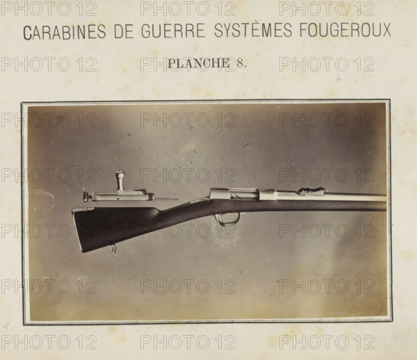 Part of a rifle and a loose safety catch, photograph, page, number: 'Planche 8.', inscription: 'Carabines de guerres systèmes Fougeroux', photographer: Edouard Magis, Liège, c. 1857 - in or before 1867, paper, albumen print, height 158 mm x width 96 mm, Image in section at the back., firearms: rifle, A sepia-toned photograph of a rifle displayed horizontally within a dark rectangular frame, showing the rear stock, trigger guard, and part of the barrel against a mottled background; the wooden stock appears dark and smooth with a metal sling swivel at its end, the bolt mechanism and sights are visible along the top of the barrel, and a detached metal bolt component rests above the rifle; the surrounding paper shows light aging spots and a narrow double-lined border around the photograph.