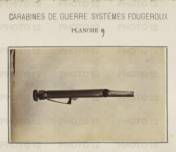 Pal of a rifle, photograph, page, number: 'Planche 9.', inscription: 'Carabines de guerres systèmes Fougeroux', photographer: Edouard Magis, Liège, c. 1857 - in or before 1867, paper, albumen print, height 158 mm x width 96 mm, Image in section at the back., firearms: rifle, A sepia-toned page shows a rectangular framed photograph of a cylindrical mechanical object placed horizontally against a plain background, with one end featuring a ridged circular knob and a short exposed rod at the opposite end; a thin angled metal lever is attached beneath the cylinder and the page around the photograph has a faint aged texture and slight spotting.