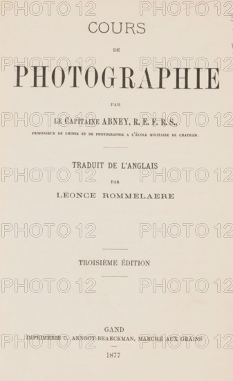 Cours de photographie, par Abney, traduit de l'Anglais par Léonce Rommelaere, book, name: '..Bennert 84.', name: 'L. Bennert, V Bennert', name: 'V Bennert', annotation: 'MAR 1993', writer (clerical worker): Sir William de Wiveleslie Abney, printer (person): C. Annoot-Braeckman, Ghent, 1877, Sir William de Wiveleslie Abney, C. Annoot-Braeckman, writer (clerical worker), printer (person), textile materials, pasteboard, biological material, paper, leather, linen (material), printing, albumen print, spanish marbled paper, stone marbled paper, height 240 mm x width 159 mm x thickness 15 mm, A centered page with a pale beige background showing various lines of dark serif typography arranged vertically, large bold display letters near the top, smaller lines of text spaced below, thin horizontal dividing lines, and faint age spots and slight paper texture across the surface.