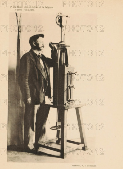 Man uses a device to measure temperatures, page, photomechanical print, cliché maker: AJ Kymeulen, c. 1891 - in or before 1896, photographer, paper, collotype, photoprint, height 154 mm x width 90 mm, Print on third unnumbered page after page 148., adult man, thermometer, A sepia-toned photograph shows a man standing beside a tall piece of apparatus mounted on a wooden stand; the man wears a dark suit with a vest and bow tie and has a mustache, his right hand rests on a horizontal part of the apparatus near his face while his left hand hangs by his side; the apparatus includes vertical columns, gears, and clamps, and stands on a sturdy tripod-like wooden base with visible crossbars, with some cables or wires draped around its components; the background is plain and light, and a narrow curtain or panel is visible behind the man at the left edge.