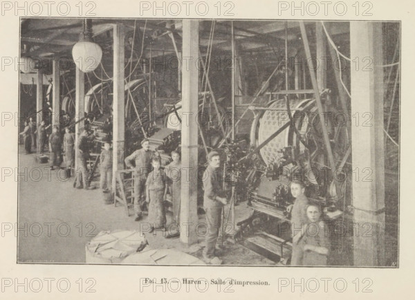 View of the interior of a printing shop in Haren, Belgium, page, photomechanical print, inscription: 'Fig. 15. - Haren: Salle d'impression.', monogram: 'AN', photographer: unknown, Haren (Brussels), cliché maker: Jean Malvaux, c. 1901 - in or before 1906, unknown, Jean Malvaux, photographer, cliché maker, Brussels, paper, autotype, height 170 mm x width 110 mm, printing, printing office, workshop-interior, paper (writing material), A wide interior scene shows a long room with tall vertical posts and beams stretching from foreground to background, overhead lighting globes hanging from the ceiling, numerous large mechanical machines with visible gears and belts aligned along the length of the room, many cables and rods suspended and connected to the machinery, groups of people standing and working beside the machines wearing plain, dark clothing and aprons, a few young individuals positioned near the front looking toward the viewer, stacks of folded material on the floor in the foregroun...