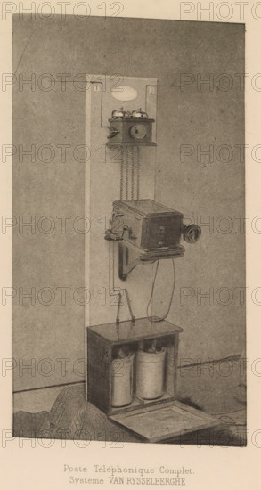 Complete telephone set, Poste Téléphonique Complet, page, photomechanical print, inscription: 'Système VAN RYSSELBERGHE', cliché maker: Bauwens (possibly), c. 1880 - in or before 1885, photographer, paper, photoaquatint, height 168 mm x width 93 mm, telephone, post, telegraph and telephone, means of communication, A vertical panel mounted against a wall holds a wall-mounted box with a round mouthpiece and two small bells on top connected by zigzag coiled wires down to a larger rectangular box below; the lower box has a crank handle on its side and a curved support bracket beneath it, with a cord hanging down to an open-topped wooden cabinet at the base that contains two cylindrical containers and a removable lid resting on the floor in front; the scene is rendered in a sepia-toned, grainy illustration style.