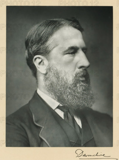 His grace the duke of Devonshire, photograph, page, annotation, inscription: '25 Old Bond St. London, W.', photographer: Bassano & Co., London, c. 1893 - c. 1903, paper, carbon print, height 226 mm x width 171 mm, Photo on frontispiece., historical persons (portraits and scenes from the life) ((full) bust portrait), A black and white portrait of a man in profile facing right showing short combed hair, a full beard and mustache, a visible ear, a high forehead, and a solemn facial expression; he is wearing a dark suit jacket with a visible lapel, a high white shirt collar, and a dark necktie, all framed by a light border around the photograph.