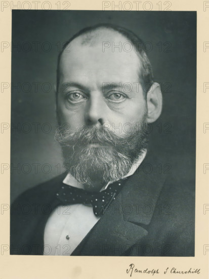 The right honorable the late lord Randolph Spencer Churchill, photograph, page, inscription: '25, Old Bond St, London, W.', annotation, photographer: Bassano & Co., c. 1890 - c. 1895, paper, carbon print, height 227 mm x width 171 mm, Person, Lord Randolph Churchill, historical persons (portraits and scenes from the life) ((full) bust portrait), A black-and-white portrait of a man shown from the shoulders up with a high forehead and closely cropped hair, a full beard and a prominent curled mustache, wearing a dark suit jacket, a white shirt with a visible stud, and a patterned bow tie; the image has a wide light-colored border around it.