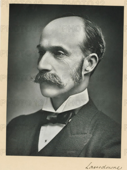 The most noble the marquis of Lansdowne, KG, photograph, page, inscription: '17, Baker St, London, W.', annotation, photographer: Russell & Sons, c. 1893 - c. 1903, paper, carbon print, height 228 mm x width 171 mm, Person, Henry Petty-Fitzmaurice (5th Marquess of Lansdowne), historical persons (portraits and scenes from the life) ((full) bust portrait), A black-and-white portrait of a middle-aged man shown in profile from the shoulders up, with a high forehead and receding hairline, neatly combed hair at the sides and back, prominent mustache with bushy ends, trimmed sideburns, and visible facial wrinkles around the eyes and cheeks; he is wearing a high collared shirt and a bow tie beneath a dark suit jacket, and the image is framed by a light border.