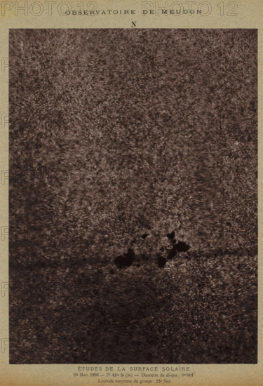 Observatoire de Meudon - études de la surface solaire, Study of the solar surface, photograph, page, inscription: '29 Mars 1893- 7h 41m 5s (m), Disc diameter: 0m901, Latitude moyenne du groupe: 23° Sud', inscription: 'Pl. V', 1893-03-29, photographer, paper, carbon print, height 230 mm x width 170 mm, physical aspects of the sun, Zon, A rectangular image framed by a textured border shows a grainy, dark surface with a mottled pattern that covers most of the area; near the lower central area there are several irregular, darker blotches forming a small cluster, and the surrounding tones vary between lighter and darker speckled textures.