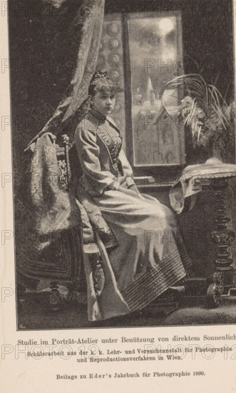 Studio portrait of an unknown woman, page, photomechanical print, monogram: 'AC', inscription: 'Studie im Porträt-Atelier unter Benützung von direktem Sonnenlicht., Beilage zu Eder's Jahbruch für Photographie 1890', maker: KK Lehr- and Versuchsanstalt für Photographie, c. 1885 - in or before 1890, KK Lehr- und Versuchsanstalt für Photographie, paper, autotypie, height 140 mm x width 93 mm, Print on twenty-fifth unnumbered page after page 400., historical persons - BB - woman, A seated woman wearing a long, high-collared dress with a fitted bodice and full skirt sits sideways on a carved wooden chair draped with a patterned fabric, her hands folded in her lap and her hair styled up; behind her is a tall window showing a bright circular light and a faint architectural silhouette, a heavy curtain hangs to one side, and a table with a cloth and a vase of long, arching leaves stands nearby, the scene rendered in a monochrome, stippled illustration style.