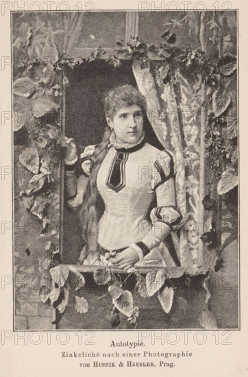 Portrait of an unknown woman, page, photomechanical print, inscription: 'Autotypie, Zinkcliché nach einer Photographie von Husnik & Häusler, Prag., Beilage zu Eder's Jahbruch für Photographie 1890', monogram: '...', maker: Husnik & Häusler, Prague, c. 1885 - in or before 1890, Husnik & Häusler, paper, autotypie, height 140 mm x width 100 mm, Print on twenty-seventh unnumbered page after page 400., historical persons - BB - woman, A monochrome image of a young woman seen from the waist up standing at a window framed by climbing plants and draped fabric, wearing a fitted dress with puffed sleeves, a high ruffled collar, and decorative trim on the bodice and sleeves; her hair is long and braided over one shoulder, one hand rests on the window frame while the other holds a small bunch of flowers, and leaves and vines cascade around the opening and along the sill.