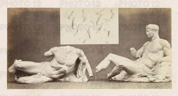 Sculptures from the Parthenon in Athens, photograph, page, inscription: 'Occasional publications, 1851-53.', British Museum, c. 1859 - in or before 1869, photographer, London, paper, albumen print, height 117 mm x width 235 mm, sculpture, A wide photograph of two pale sculptures placed on a patterned surface against a dark backdrop, with a lighter rectangular relief image mounted above them. The sculpture on the left depicts a reclining male torso without a head or arms, showing muscular contours and draped cloth beneath and beside it. The sculpture on the right shows a seated male figure with a head, one bent leg extended forward, the other leg bent at the knee, one arm partially raised with a missing hand area, and draped fabric under and around the figure. The rectangular relief above shows faint outlines of horseback figures and parts of riders rendered in low relief. The overall image has a sepia tone and visible aging marks around the borders.