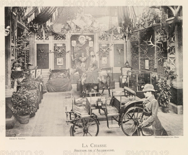 Exhibition of German hunting objects during the world exhibition in Antwerp, La Chasse Section de l'Allemagne, page, photomechanical print, photographer: Th. Lantin, Antwerp, cliché maker: Joseph Maes, 1894, Th. Lantin, Joseph Maes, photographer, cliché maker, paper, collotype, photoprint, height 160 mm x width 219 mm, spoils of the hunt, game, venison, hunting, chase, world fair, world exhibition, exhibition, show, A large indoor scene shows a room filled with mounted animal trophies and hunting paraphernalia arranged along paneled walls, with numerous antlers and skulls displayed on mounts and plaques, leafy plants in pots lining the floor, and nets and fabric draped from the ceiling; a mannequin dressed in riding attire stands beside a horse and cart positioned in the foreground, while framed pictures, a bust on a pedestal, glass display cases, and various small objects occupy tables and shelves throughout the space.