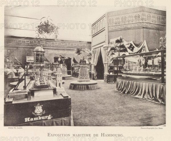 Exhibition of maritime objects from Hamburg during the World Exhibition in Antwerp, Exposition maritime de Hambourg, page, photomechanical print, photographer: Th. Lantin, Antwerp, clichémaker: Joseph Maes, 1894, paper, collotype, photogravure, height 163 mm x width 218 mm, ship-model, world fair, world exhibition, exhibition, show, A large indoor exhibition space with ornate patterned frieze along the upper walls and tall draped curtains dividing sections, containing several display cases and model maritime objects arranged on plinths and tables; a suspended hanging plant hangs near the ceiling and potted palm plants sit atop decorative round pedestals with skirted bases scattered through the room; a prominent model ship with rigging is positioned on a foreground table and other ship models are visible in glass cases and on stands; a corner structure with arched decorative panels rises at one side and fabric flags or cloths drape over part of the displays; wooden flooring covers the f...