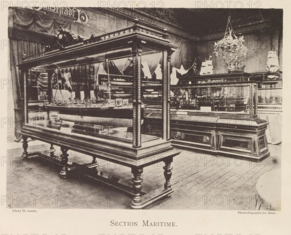 Exhibition of ship models during the World Exhibition in Antwerp, Section Maritime, page, photomechanical print, photographer: Th. Lantin, Antwerp, clichémaker: Joseph Maes, 1894, paper, collotype, photoprint, height 160 mm x width 218 mm, ship-model, world fair, world exhibition, exhibition, show, A room filled with large wooden display cases with glass sides and ornate carved legs and trim, each case containing detailed ship models visible through the glass; a suspended miniature ship hanging from the ceiling; draped fabric and flags on the walls behind the cases; wooden floorboards beneath the display furniture.