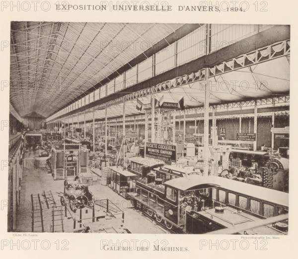 Galerie des machines, Interior of the machine hall during the World Exhibition in Antwerp, page, photomechanical print, photographer: Th. Lantin, Antwerp, cliché maker: Joseph Maes, 1894, paper, collotype, photogravure, height 163 mm x width 218 mm, interior, representation of a building, world fair, world exhibition, exhibition, show, machines, parts of machines, tools and appliances, A wide interior view of a large industrial exhibition hall with a high arched roof supported by a grid of metal trusses and rows of tall vertical columns, an upper gallery with large paneled windows running along the length of the space, and decorative draped fabric along a horizontal beam; the floor area is filled with rows of large machines and locomotives positioned on tracks, various mechanical components, display stands, and scaffolding, with signs and banners mounted above some exhibits; a foreground locomotive with a visible cab and boiler sits on rails, other machinery and engine parts occupy the...