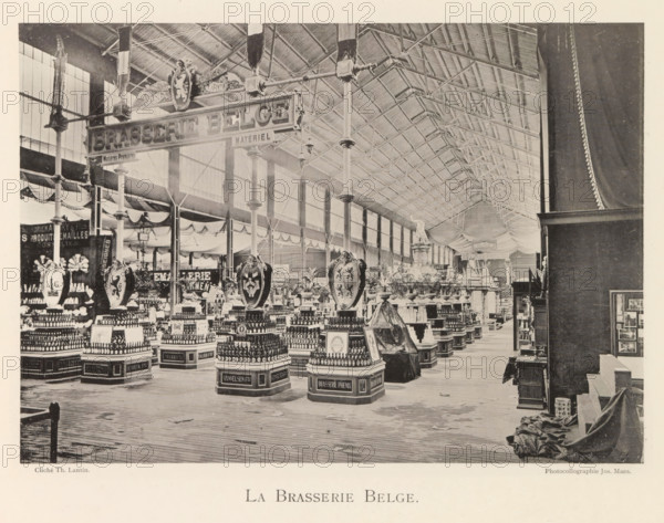 Exhibition of Belgian foodstuffs during the World Exhibition in Antwerp, La Brassie Belge, page, photomechanical print, photographer: Th. Lantin, Antwerp, clichémaker: Joseph Maes, 1894, paper, collotype, photogravure, height 155 mm x width 218 mm, industries, food, drink, stimulants, world fair, world exhibition, exhibition, show, A large indoor exhibition hall with a high vaulted roof supported by tall iron columns and trusses, rows of display tables and pedestals arranged beneath the roof, ornate hanging shields and decorative emblems suspended above several displays, numerous stacked bottles and packaged products arranged in pyramidal formations on labeled bases, draped fabric and garlands along the upper walls and between columns, a wooden plank floor extending toward the foreground, a curtained partition and covered objects to the right, and large paned windows along the left wall letting light into the space.