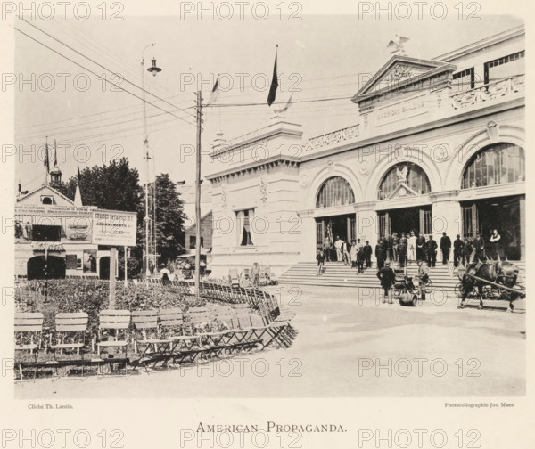 American propaganda, Square in front of the American pavilion at the World's Fair in Antwerp, page, photomechanical print, photographer: Th. Lantin, Antwerp, printer (person): Joseph Maes, 1894, Th. Lantin, Joseph Maes, photographer, printer (person), paper, collotype, photogravure, height 162 mm x width 219 mm, façade (of house or building), village square, world fair, world exhibition, World Exhibition 1894 (Antwerp), A wide sepia-toned street scene shows a large neoclassical building with ornate stonework, arched windows and a flight of steps leading to open doorways where groups of men in period clothing and uniforms stand and converse, an eagle sculpture and decorative frieze atop the facade, flags on poles projecting from the roof, a horse-drawn carriage and a few bicycles near the entrance, rows of folding chairs arranged in front of the building curving across a paved area, a lamppost and utility pole with overhead wires crossing the sky, a smaller pavilion-like structure with ...