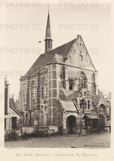 Au vieil Anvers - Chapelle St-Nicolas, Exterior of the Sint-Niklaas Chapel in Antwerp, page, photomechanical print, photographer: Th. Lantin, Antwerp, printer (person): Joseph Maes, 1894, printer (person), paper, collotype, photoprint, height 218 mm x width 161 mm, facade (of house or building), parts of church exterior and annexes: chapel, Sint-Niklaaskapel, A large stone church building fills the image, showing a tall steep roof with a pointed spire rising from a small tower near the center, lancet windows with tracery along the side, and a high gabled facade with a large arched window. The exterior walls display alternating light and dark stone bands and buttressed corners, with smaller attached structures and pitched roofs at street level. In front of the church there is a courtyard with cobblestones, wooden benches and racks, a crucifix mounted on a pole, and a decorative column topped by a sculpted figure. Rooftops and partial facades of neighboring buildings are visible at the e...