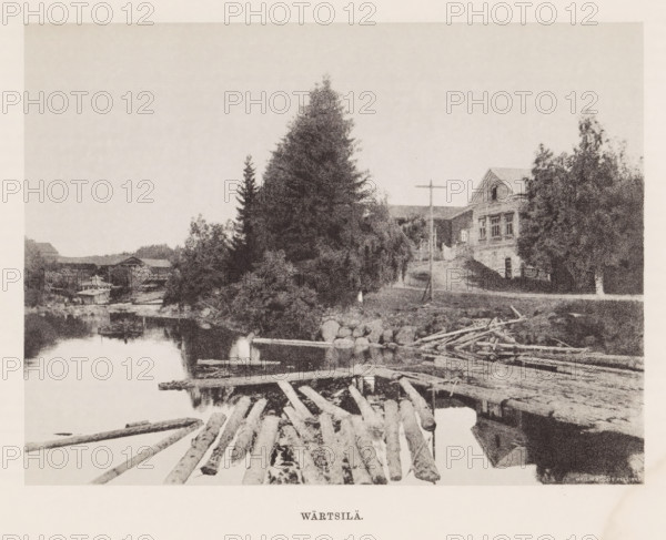 View of tree trunks in the water and houses around the water, Wärtsilä, page, photomechanical print, photographer: Impi Backman, cliché maker: anonymous, printer (person): Weilin & Göös, c. 1888 - c. 1893, printer (person), paper, autotypie, height 166 mm x width 222 mm, landscapes with waters, waterscapes, seascapes (in the temperate zone), civic architecture, edifices, dwellings, Karelia, A riverside scene showing a calm body of water with floating logs and a simple wooden raft in the foreground, a pile of timber and scattered branches along the shore, a rocky bank leading up to a dirt path, tall evergreen trees and other dense foliage rising on the riverbank, a wooden building with a pitched roof partially visible behind the trees, a simple wooden cross mounted near the path, and a treeline and additional low buildings visible across the water.