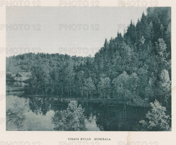 View of a river and the woods on the bank, Tirrin Mylly - Ruskeala, page, photomechanical print, photographer: Impi Backman, cliché maker: anonymous, printer (person): Weilin & Göös, c. 1888 - c. 1893, printer (person), paper, autotypie, height 167 mm x width 206 mm, trees, river, civic architecture, edifices, dwellings, Karelia, A landscape photograph showing a densely treed hillside on the right and a lower wooded area extending across the middle, with a calm body of water at the bottom reflecting the trees; a simple building with a pitched roof sits near the water at the left, partially obscured by trees, and the image has a wide pale sky above the treeline.