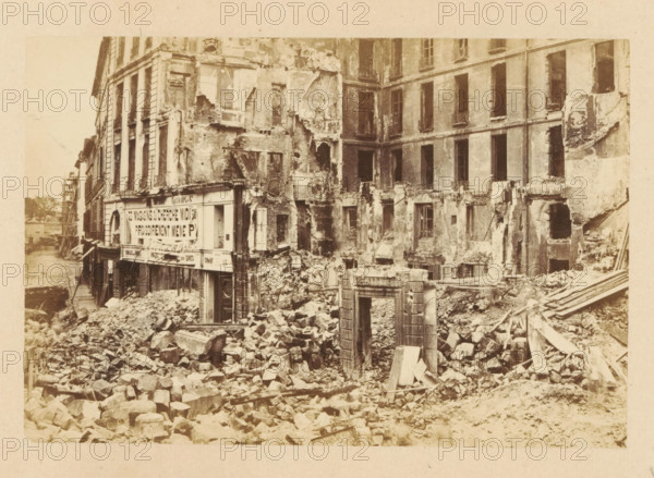 Carrefour de la Croix Rouge, View of a destroyed building at Carrefour de la Croix Rouge, photograph, page, 1871, photographer, paper, albumen print, albumendruk, height 101 mm x width 151 mm, street, theater (building), Paris, A sepia-toned scene of a heavily damaged multi-story building with large sections of facade missing and exposed interior walls, empty window openings, and crumbling plaster. The ground in front of the building is covered in a chaotic pile of rubble, broken stones, and timber debris. A partially intact doorway frame stands amid the debris, and fragments of architectural details lie scattered. Adjacent buildings show worn exteriors and shuttered or open windows, while a narrow street or waterway runs alongside the row of structures. The overall appearance is one of widespread structural collapse and scattered building materials.