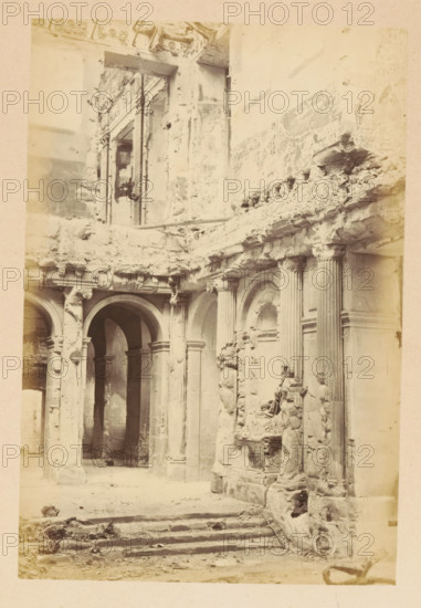 View of the ruined interior of the Tuileries Palace in Paris, Palais des Tuileries - vue intérieure, photograph, page, Tuileries Palace, 1871, photographer, Paris, paper, albumen print, albumendruk, height 150 mm x width 101 mm, ruin of a dwelling, house, castle, palace, A sepia-toned photograph of a ruined stone interior showing arched doorways and fluted columns with damaged capitals and bases, crumbling masonry and exposed rubble along the upper ledges, carved niches and ornamental stonework partly broken away, a set of worn stone steps leading up into the space, and fragments of stone and debris scattered across the floor.